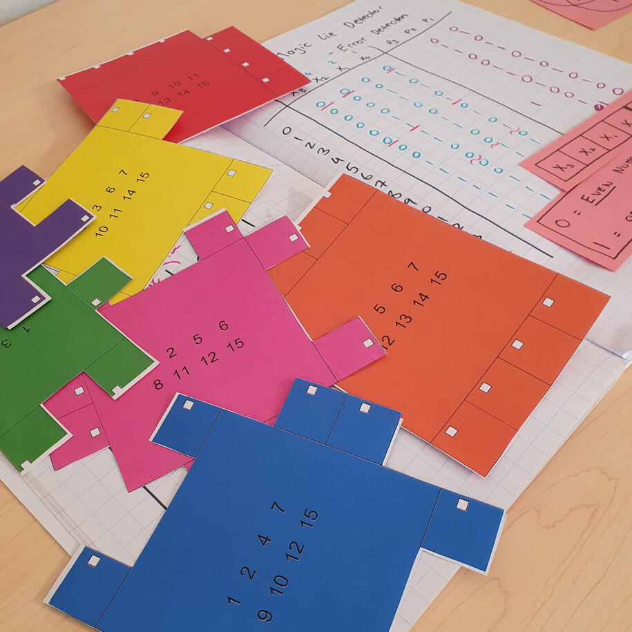 Colourful paper puzzle pieces used in a hands-on Hamming code magic trick, teaching error-correcting codes